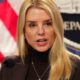 Pam Bondi speaking at DOJ podium in 2025, amid gun registry controversy - official portrait with American flag background